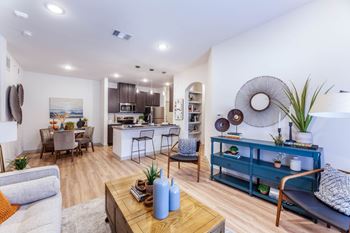 A modern living room with a kitchen in the background.